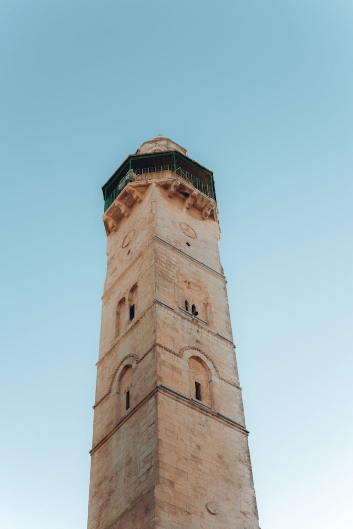 Low angle shot of a historic minaret with intricate architecture against a clear blue sky.